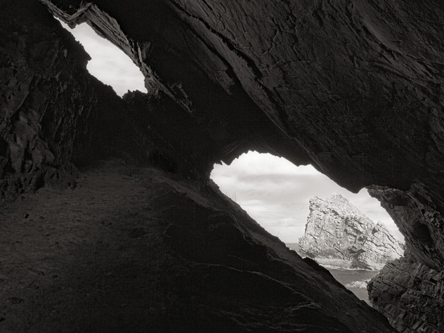 The distant well-known lump of rock has been photographed many many times, but I've never seen a single shot of it from within the adjacent cave.